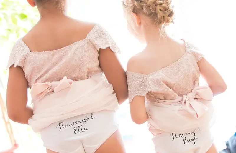 Two flower girls in pale pink dresses seen from behind