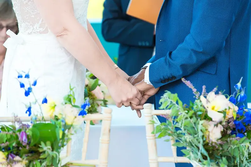 Close-up of the couple's hands during the ceremony with flowers in the foreground