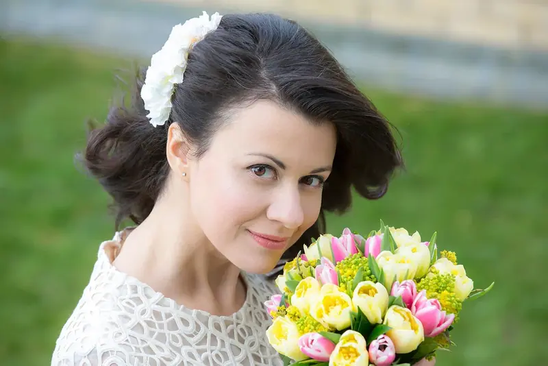 Bride with a white flower in her hair holding a bouquet of tulips