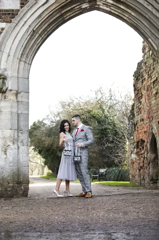 Bride and groom standing beneath a stone archway