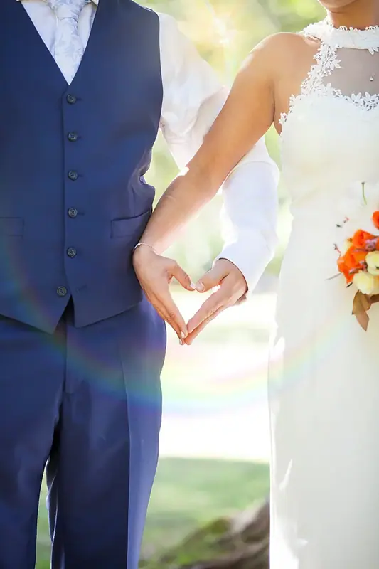 Bride and groom holding hands, close-up of a bouquet and the groom's waistcoat