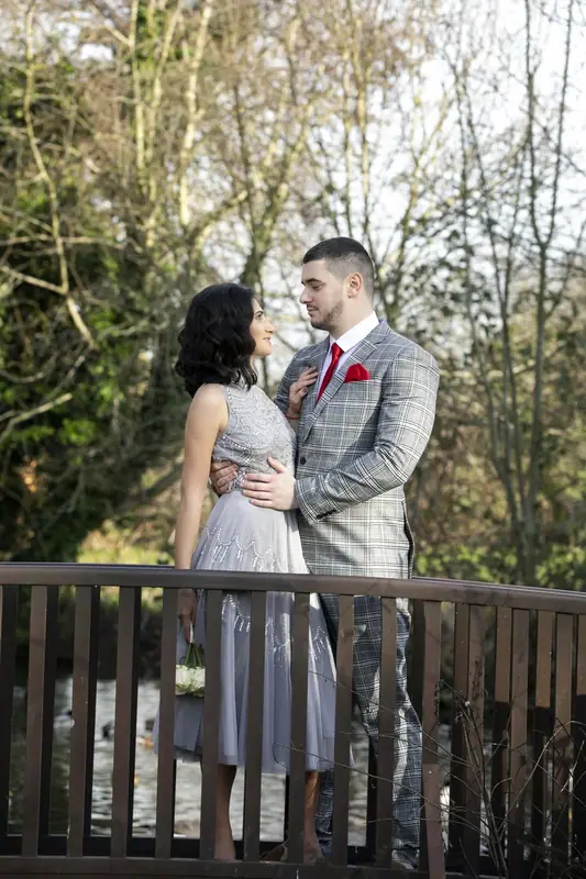 Bride and groom embracing on a wooden bridge in a park