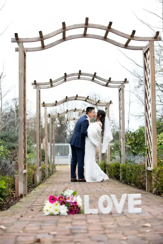 Bride and groom beneath a garden pergola with large letters spelling LOVE