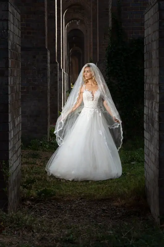 Bride in a full white gown standing in a brick archway