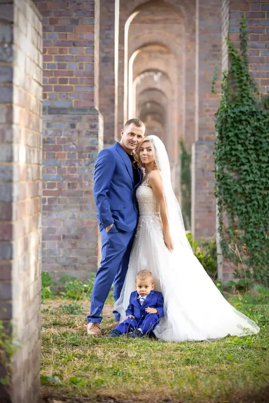 Bride and groom with a small boy standing in a brick archway