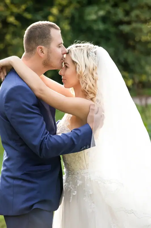 Bride and groom in a blue suit embracing outdoors