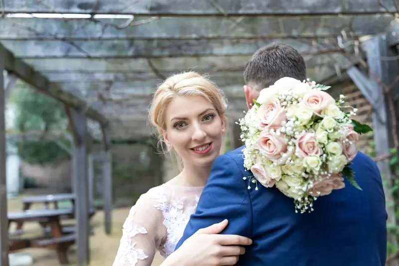 Smiling bride holding a bouquet with her arm around the groom, close-up
